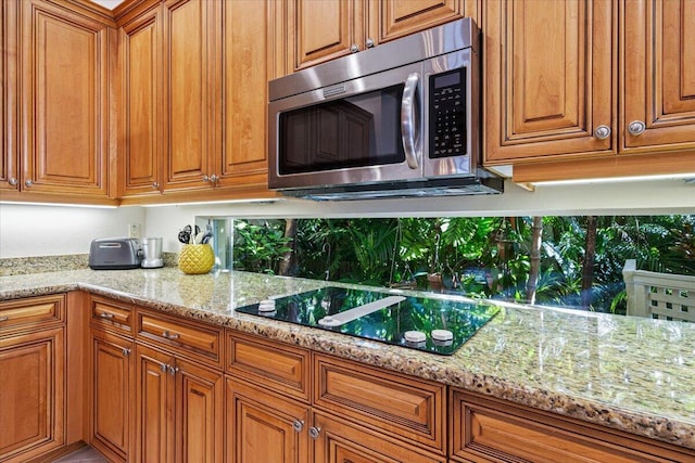 kitchen with black electric cooktop, backsplash, and light stone counters