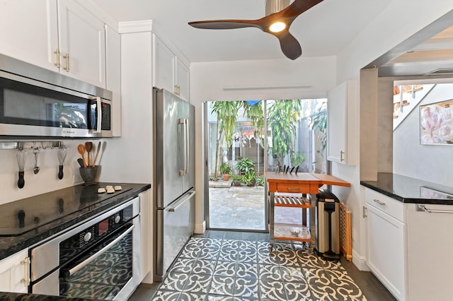 kitchen with stainless steel appliances, white cabinetry, ceiling fan, and dark stone counters