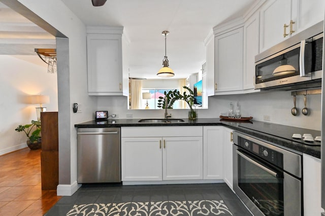 kitchen with appliances with stainless steel finishes, dark tile patterned flooring, sink, and white cabinets