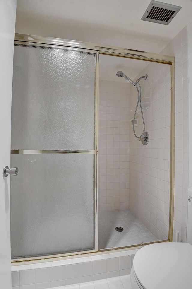 bathroom featuring toilet, walk in shower, and tile patterned flooring