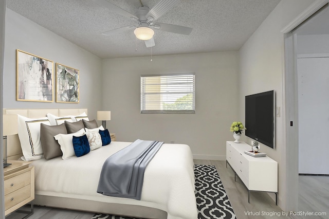 bedroom with a textured ceiling, light hardwood / wood-style flooring, and ceiling fan