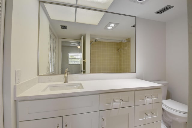 bathroom featuring toilet, vanity, and tiled shower