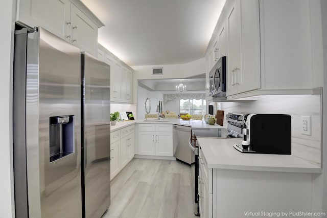 kitchen with appliances with stainless steel finishes, sink, white cabinets, light hardwood / wood-style flooring, and light stone counters