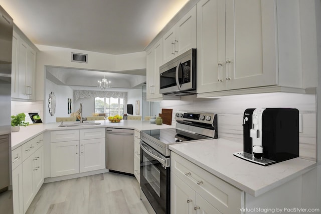 kitchen with sink, white cabinetry, pendant lighting, and stainless steel appliances