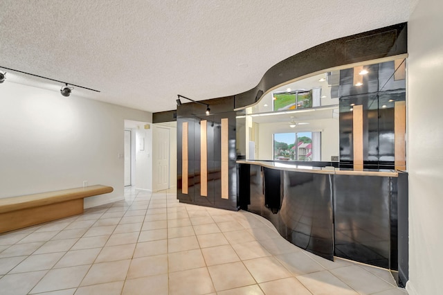 interior space with light tile patterned floors, rail lighting, and a textured ceiling