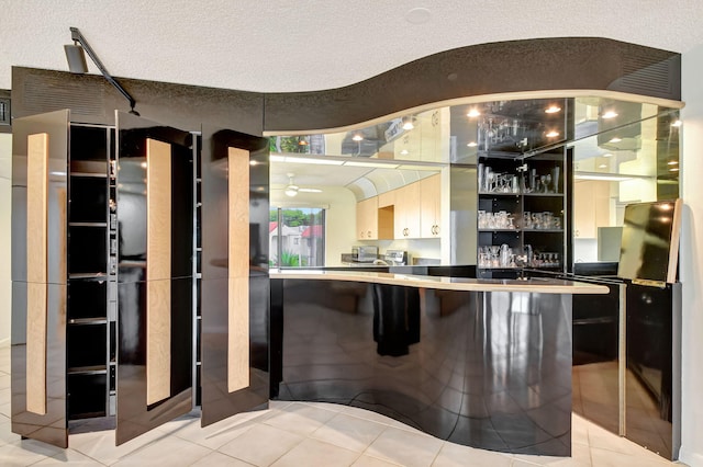 bar with light tile patterned flooring, ceiling fan, and a textured ceiling