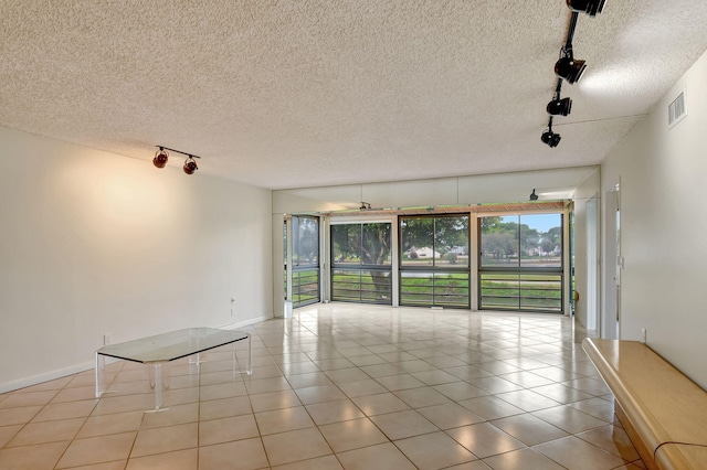 unfurnished room featuring light tile patterned floors, track lighting, and a textured ceiling