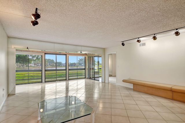 tiled empty room featuring track lighting and a textured ceiling