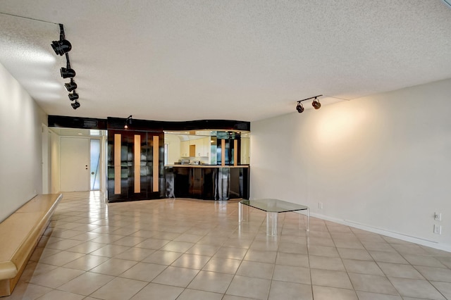 unfurnished living room with light tile patterned flooring, rail lighting, and a textured ceiling