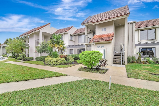 view of front of home with a balcony and a front yard