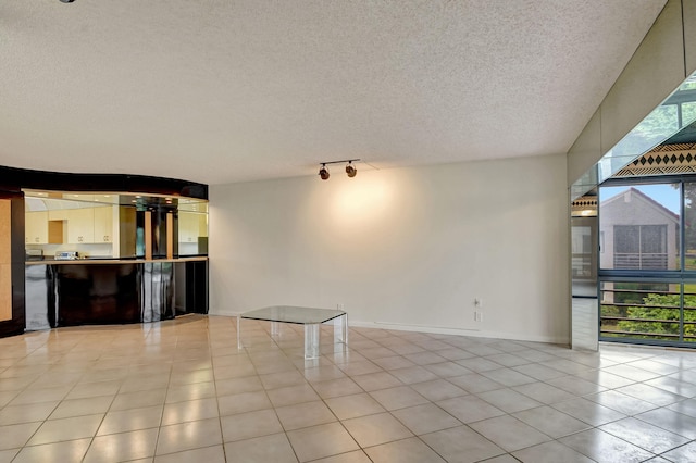 spare room featuring expansive windows, rail lighting, a textured ceiling, and light tile patterned floors