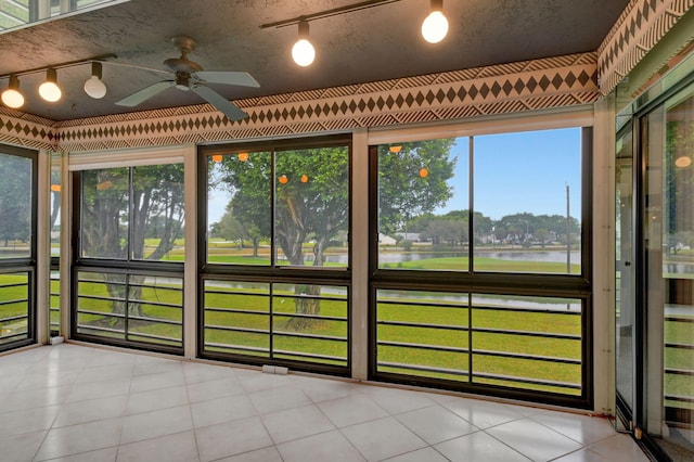 unfurnished sunroom with a water view, a wealth of natural light, and ceiling fan