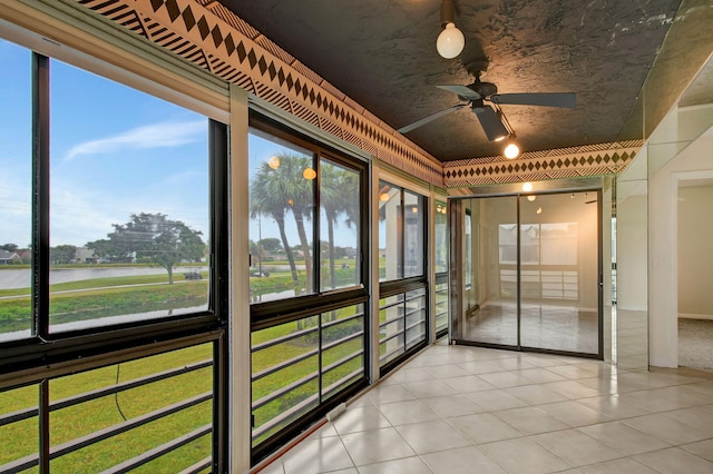 unfurnished sunroom with ceiling fan and a water view