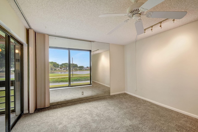 carpeted spare room featuring rail lighting, ceiling fan, and a textured ceiling