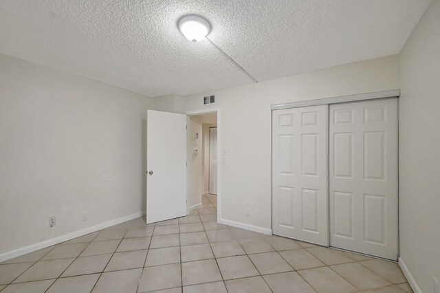 5519 Fairway Park Dr Unit 202, Boynton Beach, FL 33437 - unfurnished bedroom featuring a textured ceiling, baseboards, a closet, and light tile patterned floors