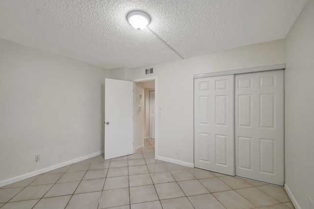 unfurnished bedroom featuring light tile patterned flooring, a closet, and a textured ceiling