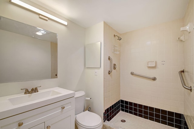 bathroom with tiled shower, vanity, and toilet