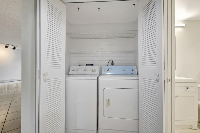 laundry room with light tile patterned floors, a textured ceiling, and washing machine and clothes dryer