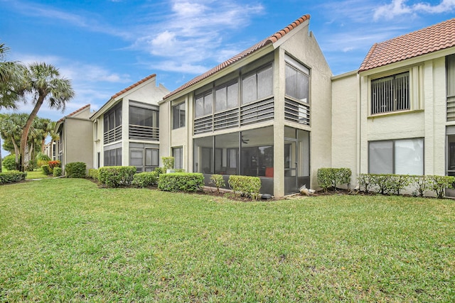 5519 Fairway Park Dr Unit 202, Boynton Beach, FL 33437 - back of house featuring a sunroom, a tiled roof, stucco siding, and a lawn