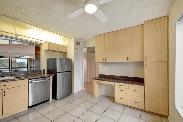 kitchen featuring light brown cabinetry, sink, built in desk, and appliances with stainless steel finishes