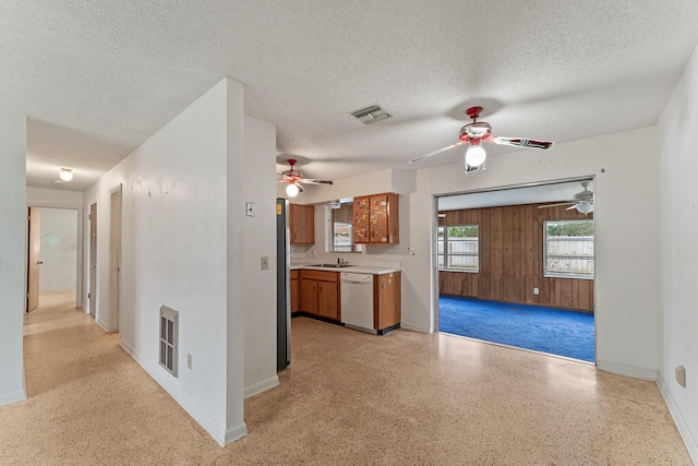 kitchen with ceiling fan, a textured ceiling, dishwasher, and wood walls