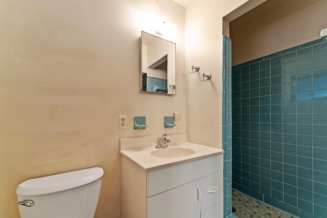 bathroom featuring a tile shower, toilet, and vanity