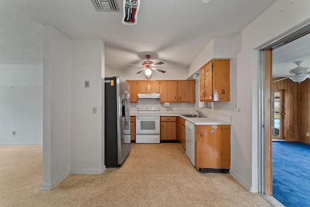 kitchen with white appliances, a textured ceiling, sink, ceiling fan, and wood walls