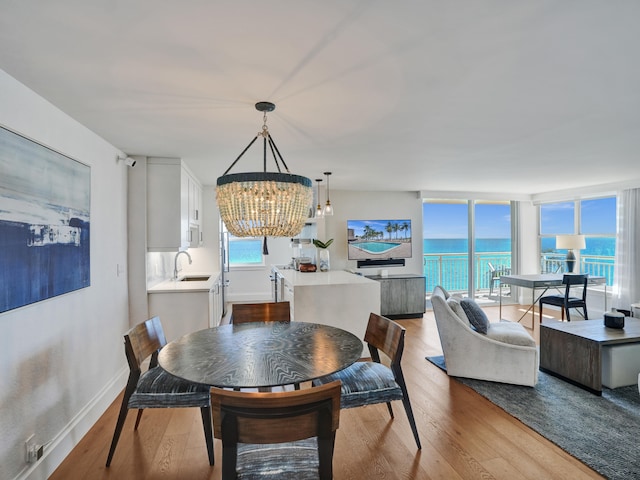 dining space with a chandelier, a wall of windows, wood finished floors, and baseboards