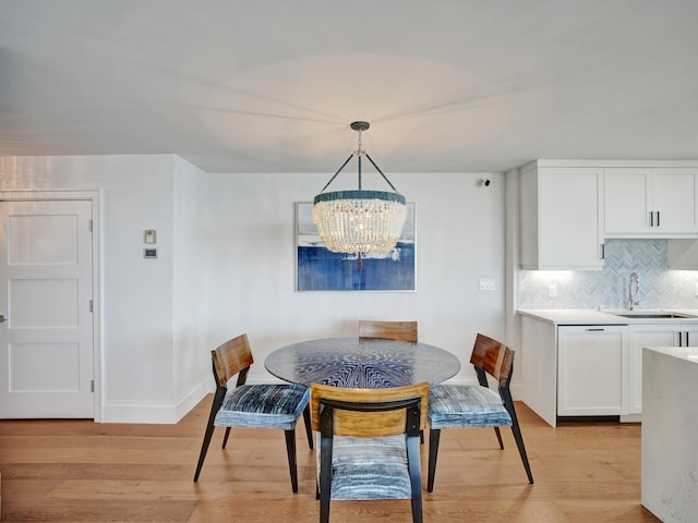 dining space featuring sink, a notable chandelier, and light wood-type flooring