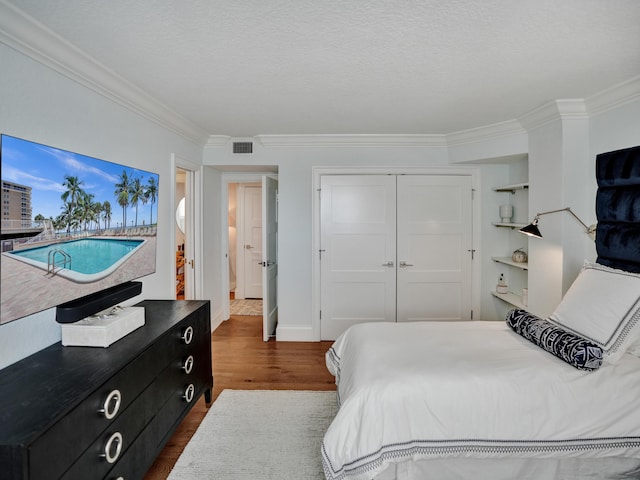 bedroom featuring dark hardwood / wood-style flooring, ornamental molding, a closet, and a textured ceiling