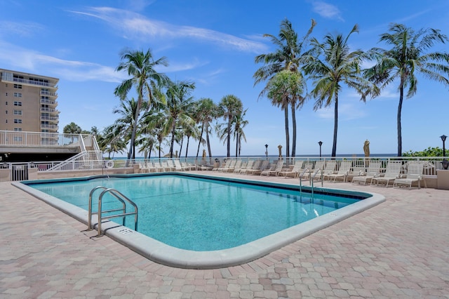 view of pool with a patio and a water view