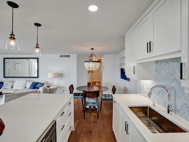 kitchen featuring hanging light fixtures, white cabinetry, sink, and tasteful backsplash