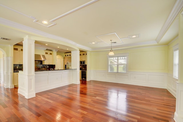 unfurnished living room with crown molding and ornate columns