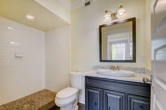 bathroom with toilet, vanity, crown molding, and tiled shower