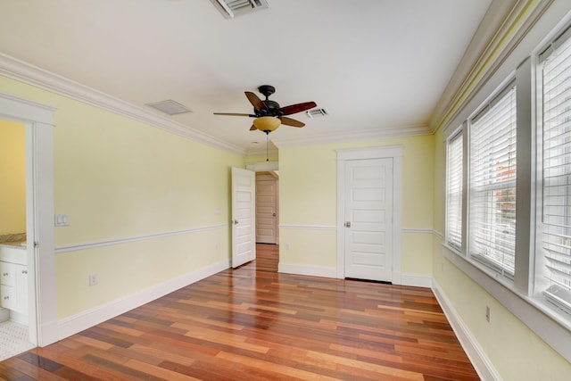 unfurnished bedroom featuring ceiling fan, crown molding, multiple windows, and hardwood / wood-style flooring