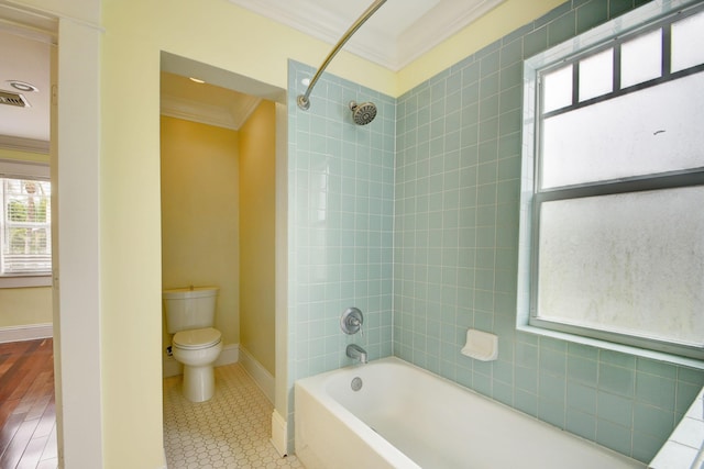 bathroom featuring tile patterned floors, toilet, ornamental molding, and tiled shower / bath