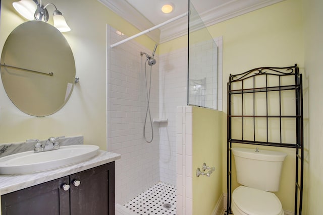 bathroom with vanity, toilet, crown molding, and a tile shower