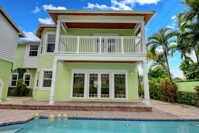 rear view of property with a balcony, french doors, and a patio