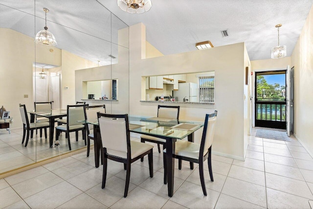 dining area featuring a notable chandelier, vaulted ceiling, and light tile patterned floors