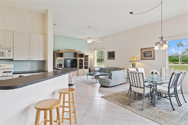 tiled dining area with ceiling fan with notable chandelier