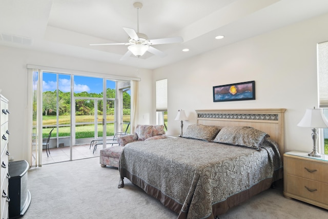 bedroom with a tray ceiling, light colored carpet, and ceiling fan