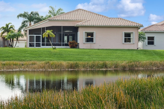 rear view of property featuring a water view, a sunroom, and a lawn