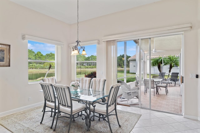 tiled dining space featuring an inviting chandelier, plenty of natural light, and a water view