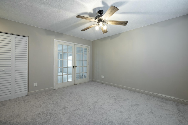 spare room featuring light carpet, ceiling fan, french doors, and a textured ceiling