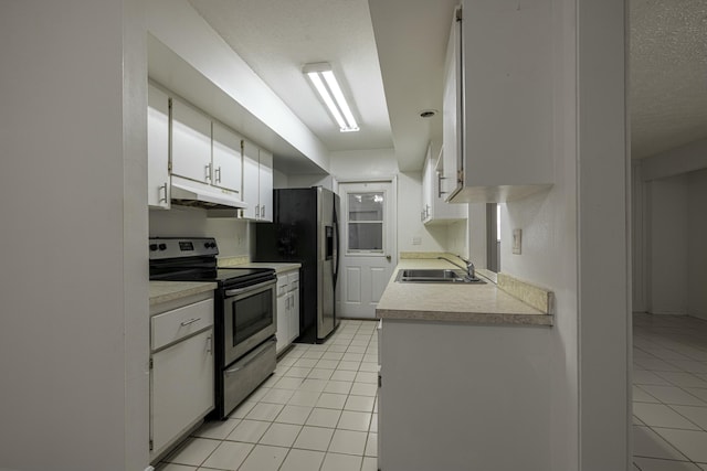 kitchen with sink, light tile patterned floors, appliances with stainless steel finishes, a textured ceiling, and white cabinets