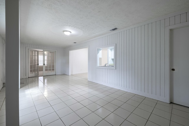 tiled spare room with french doors and a textured ceiling