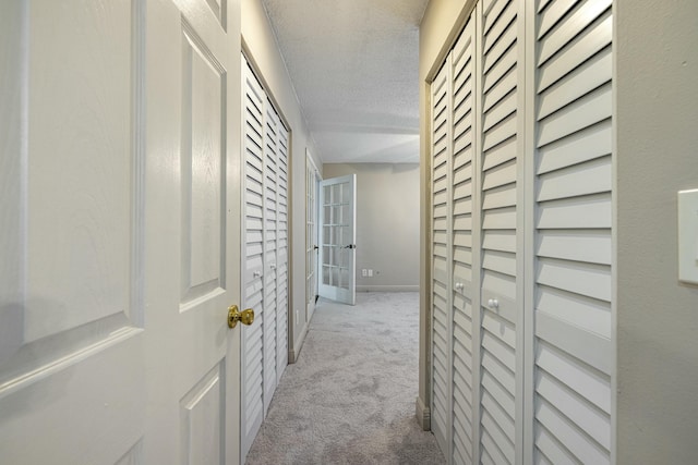 corridor featuring light carpet and a textured ceiling