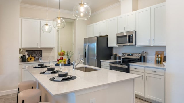 kitchen featuring pendant lighting, white cabinets, stainless steel appliances, a kitchen island with sink, and a breakfast bar