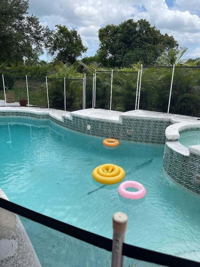 view of swimming pool with an in ground hot tub