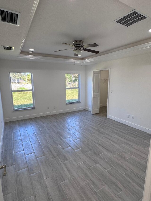 unfurnished room with ceiling fan, a tray ceiling, and light hardwood / wood-style flooring